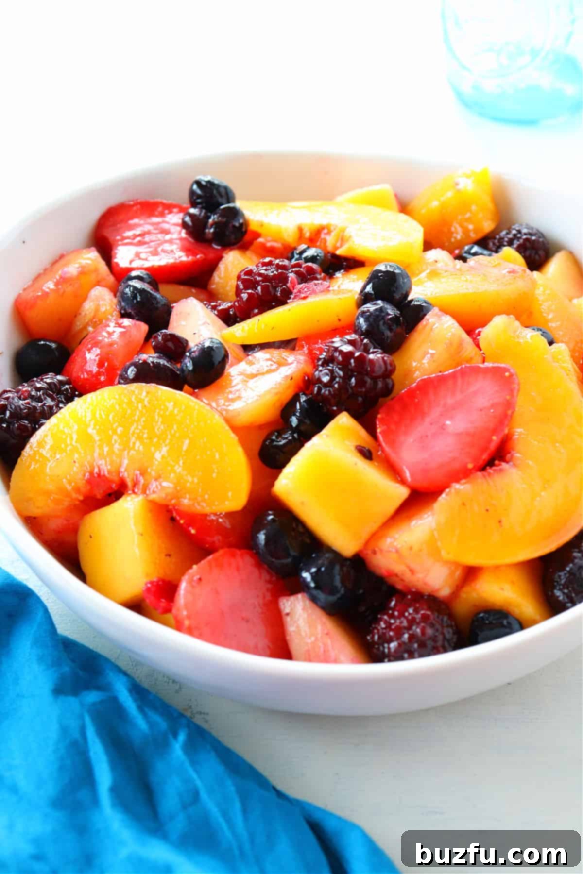 A beautiful white bowl brimming with colorful frozen fruit, ready to be tossed.