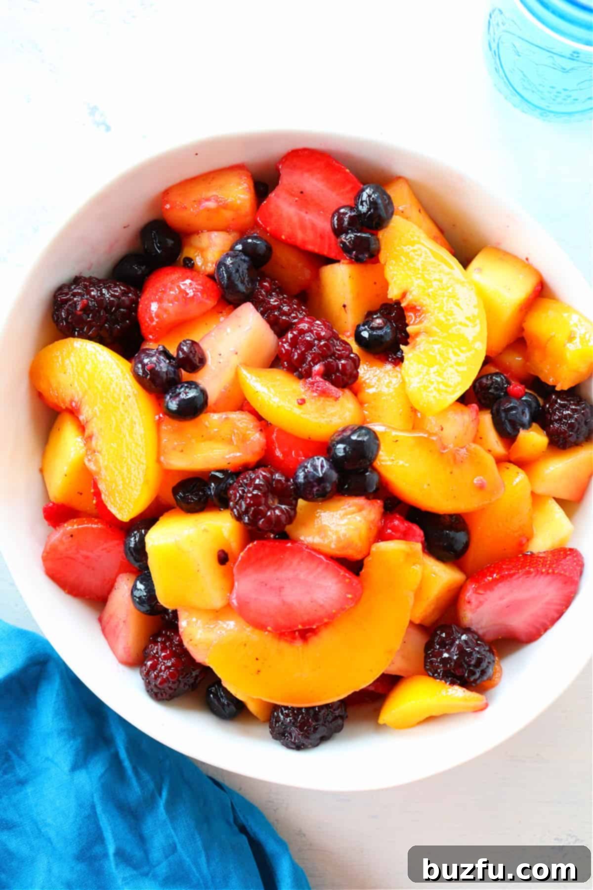 An overhead shot of a vibrant Frozen Fruit Salad in a white bowl, garnished with fresh mint.