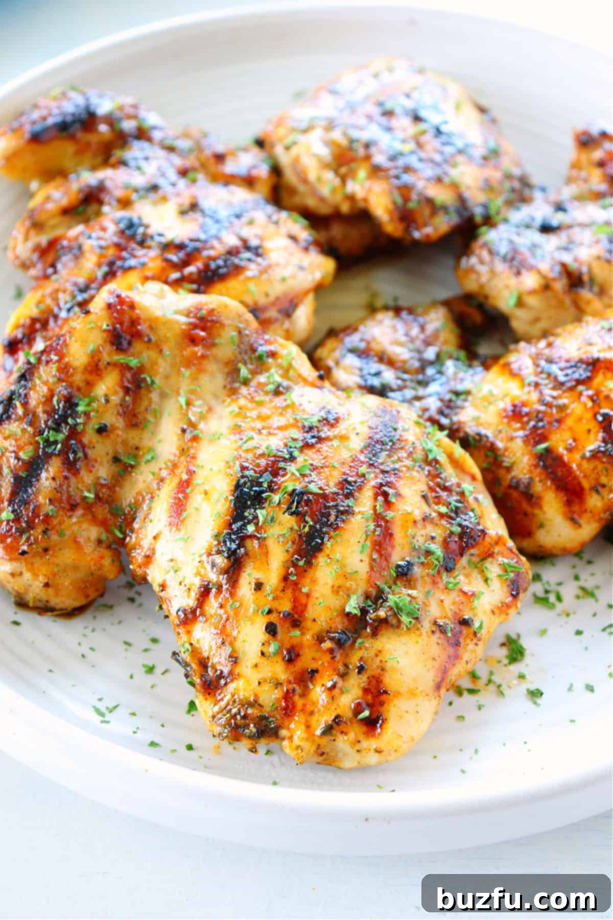 Grilled chicken thighs served on a black plate, with a perfectly charred exterior.