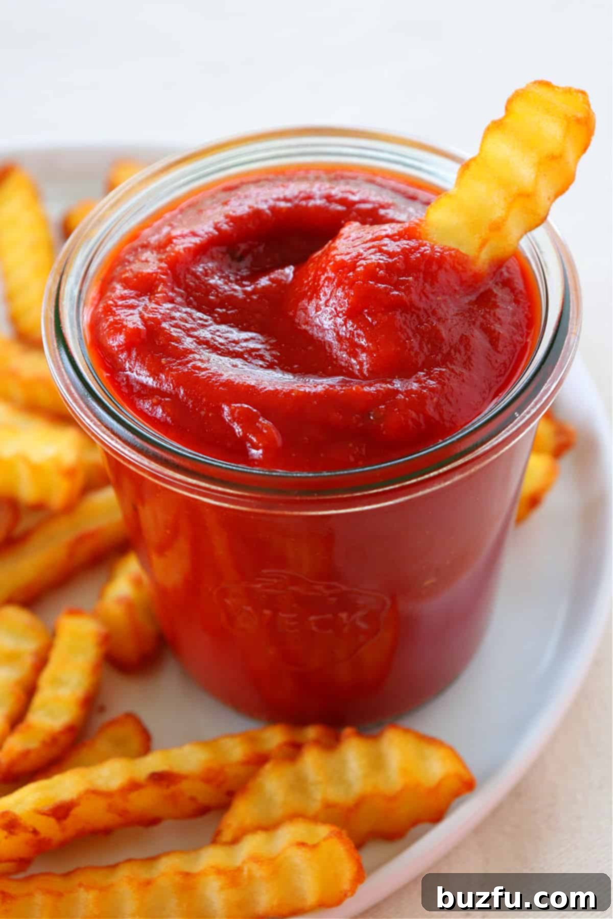 Ketchup from Scratch with Fries A glass jar of homemade ketchup surrounded by crispy french fries, ready for dipping.