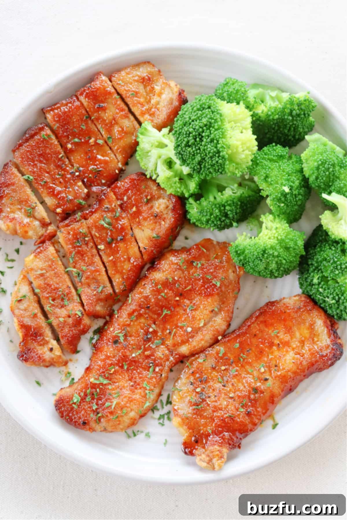 Air Fryer Pork Chops Recipe: Juicy & Flavorful A plate featuring perfectly cooked air fryer pork chops alongside vibrant green steamed broccoli, ready to be served.