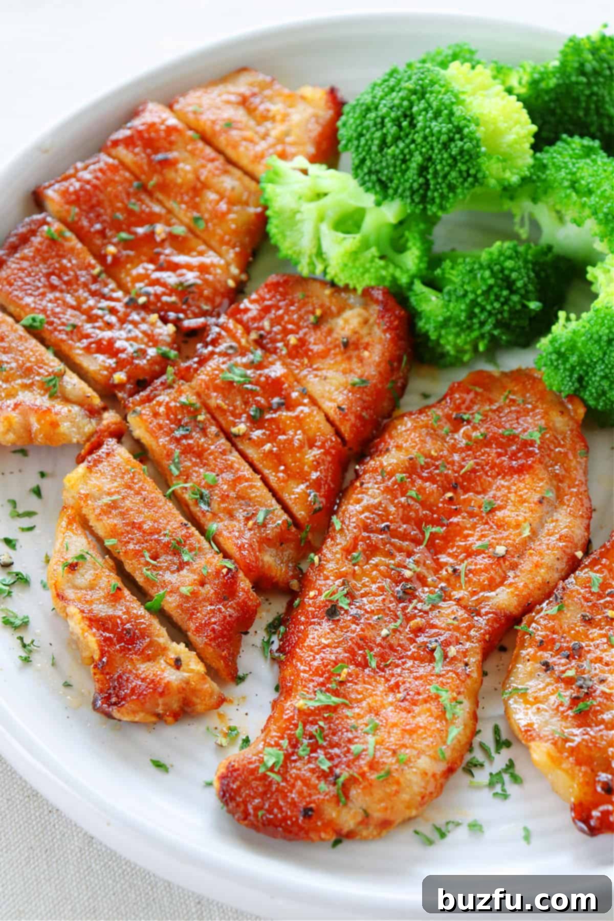 Easy & Healthy Air Fryer Pork Chops Four perfectly cooked air fryer pork chops arranged neatly on a white plate, highlighting their golden brown exterior.