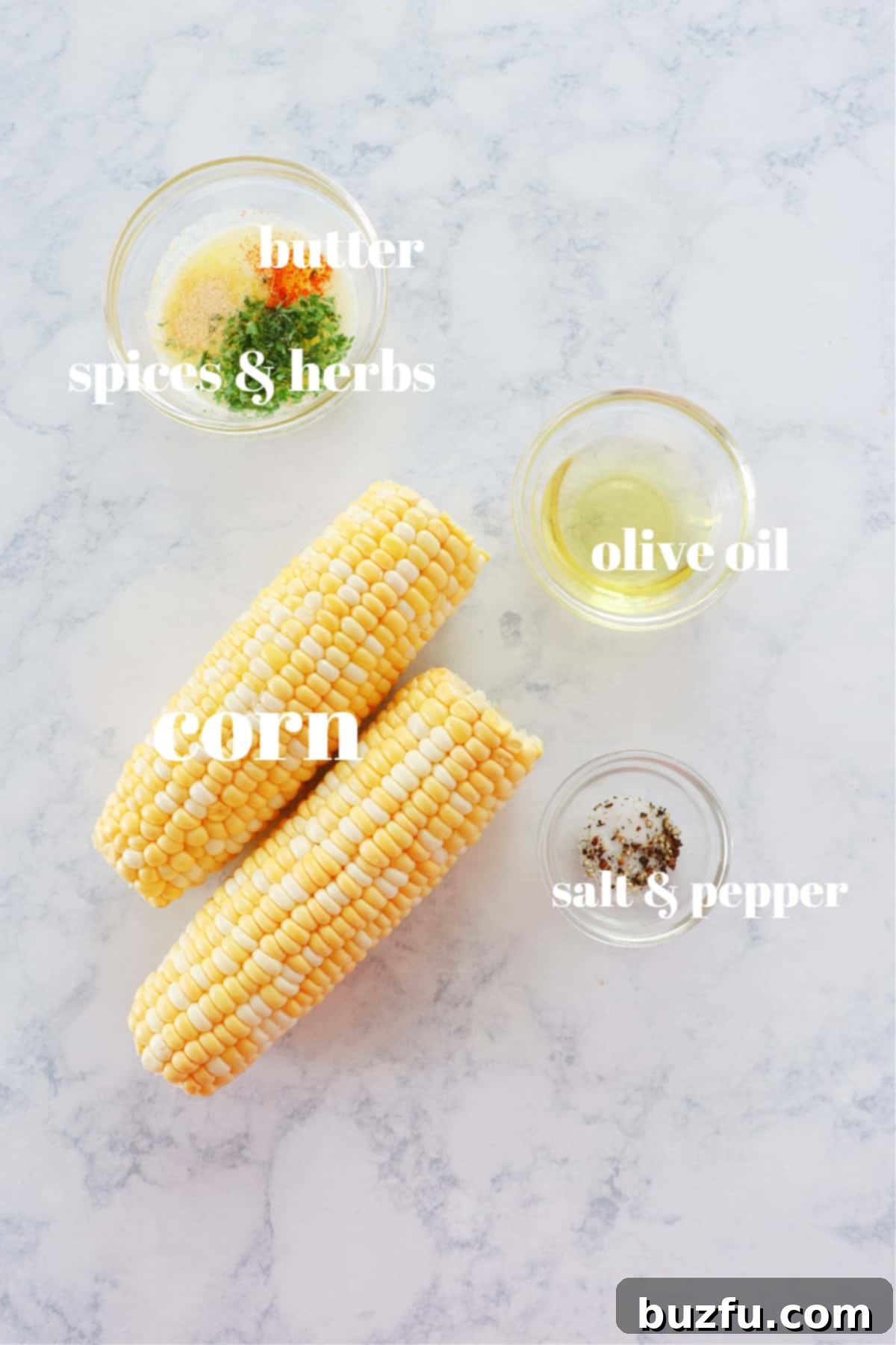 Fresh corn on the cob, olive oil, salt, pepper, butter, paprika, garlic powder, and parsley arranged on a marble surface.