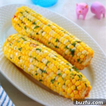 Cooked corn on a white plate with a side of seasoned butter.