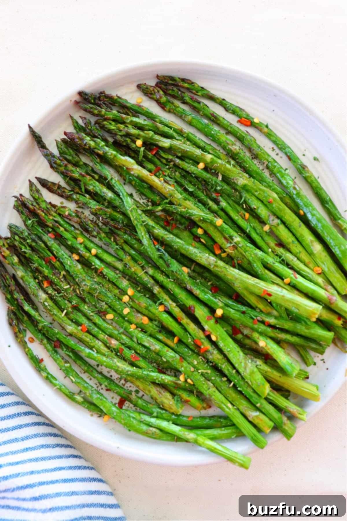 Crispy air-fried asparagus spears on a white plate, ready to be served.