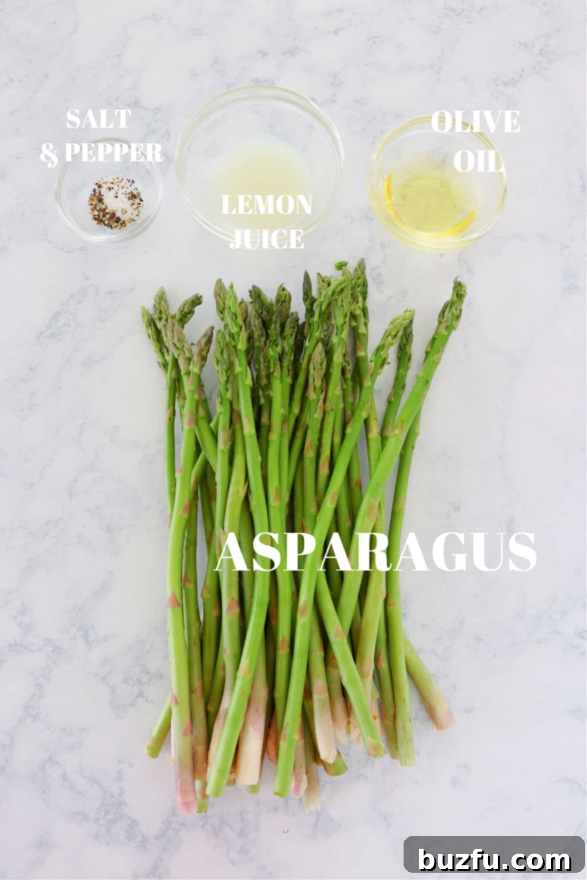 Fresh asparagus, olive oil, lemon, salt, and pepper on a marble board, ingredients for air fryer asparagus.