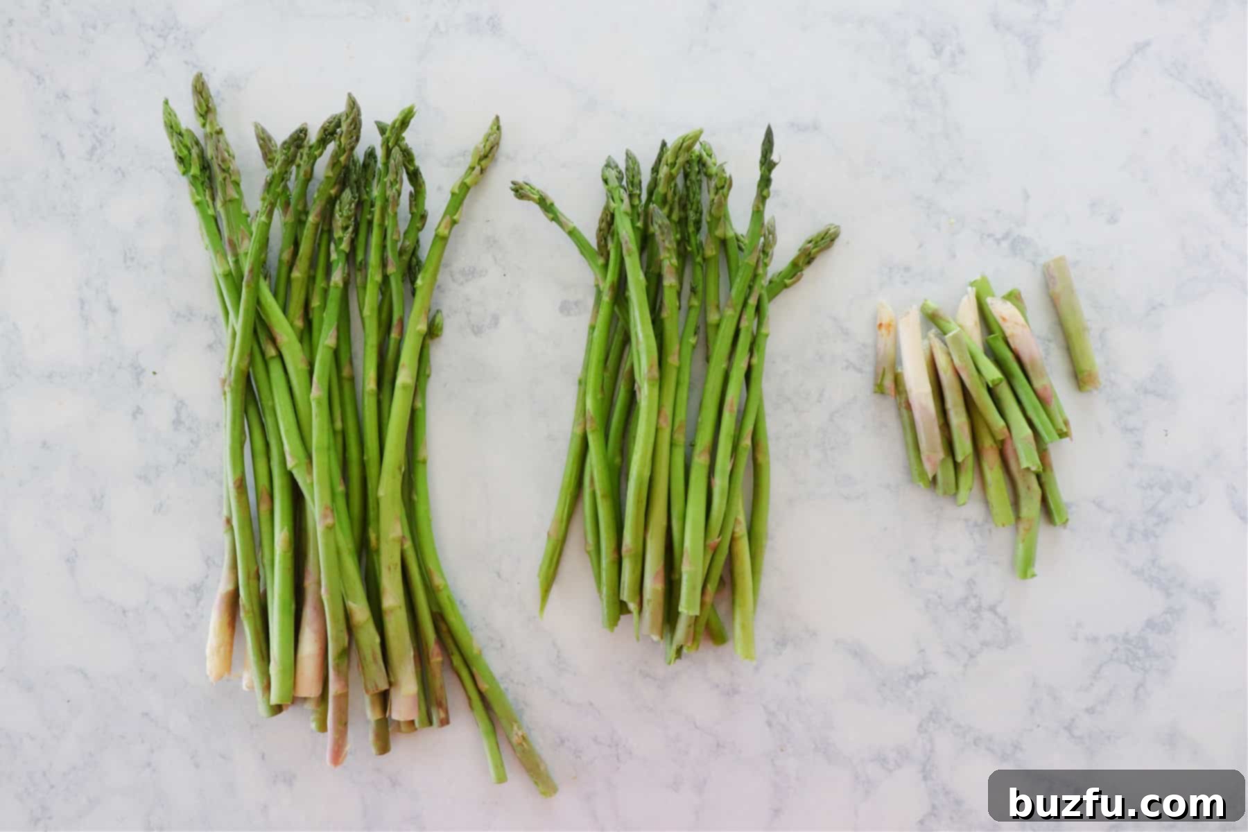 A hand snapping the woody end off an asparagus spear, demonstrating how to prepare asparagus for cooking.