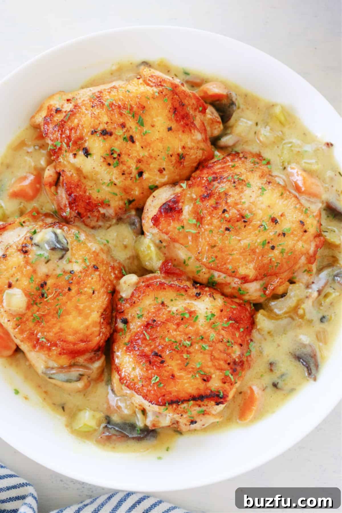 chicken fricassee recipe Chicken thighs with veggie sauce in serving dish.