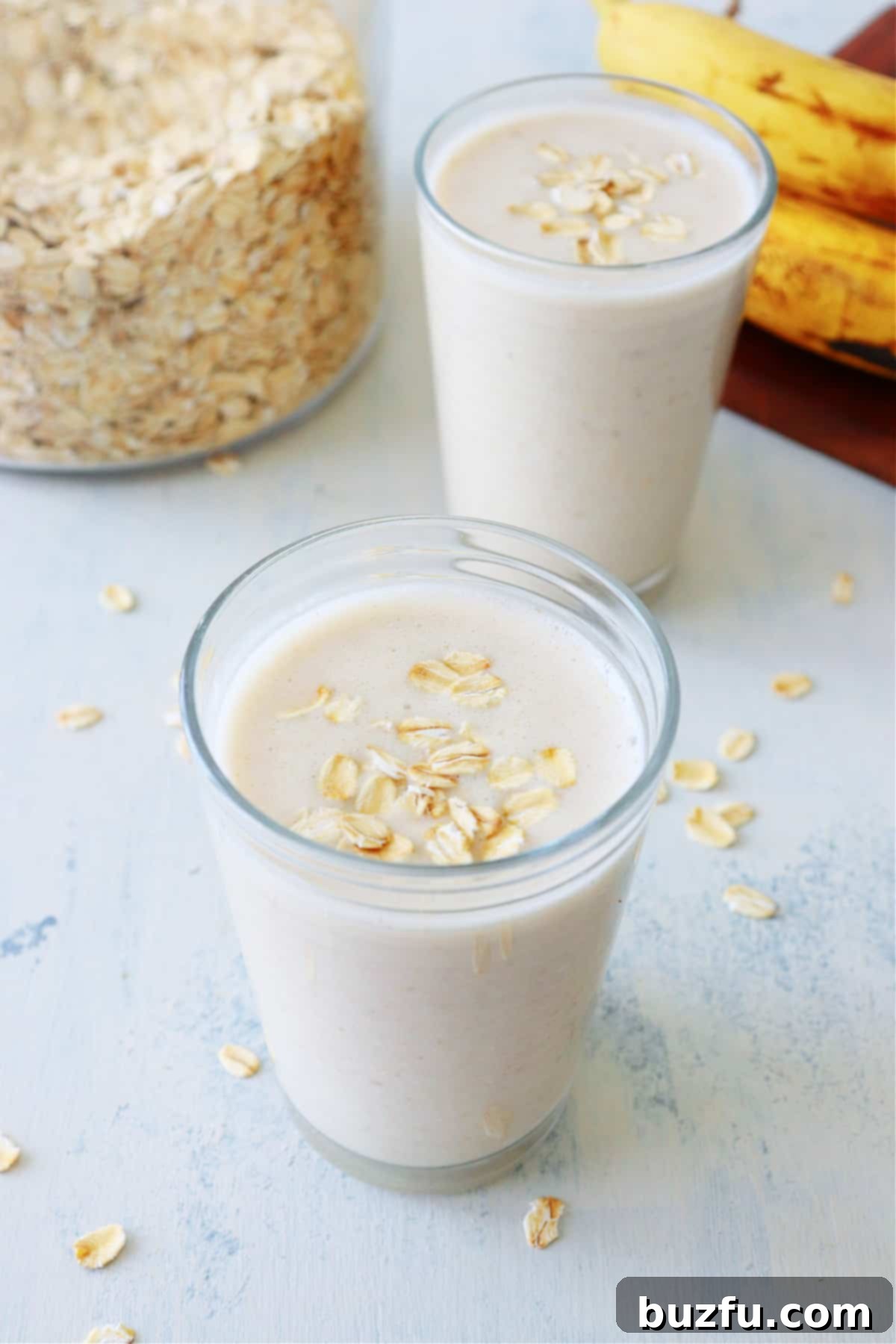 Two vibrant oatmeal smoothies in elegant glasses, garnished with a sprinkle of oats, ready to be enjoyed as a healthy breakfast.
