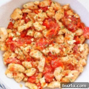 Chicken with tomatoes and feta in a skillet.