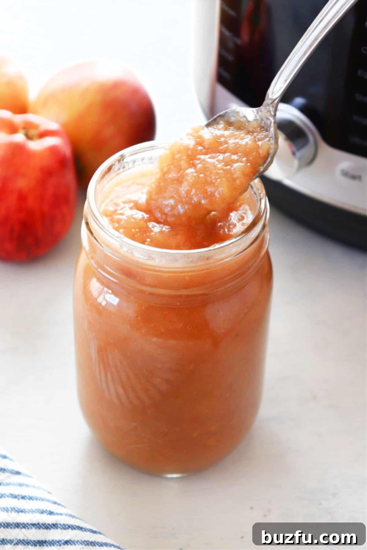 Instant Pot applesauce sugar free Applesauce in a glass jar next to an Instant Pot on a countertop, ready for enjoyment.