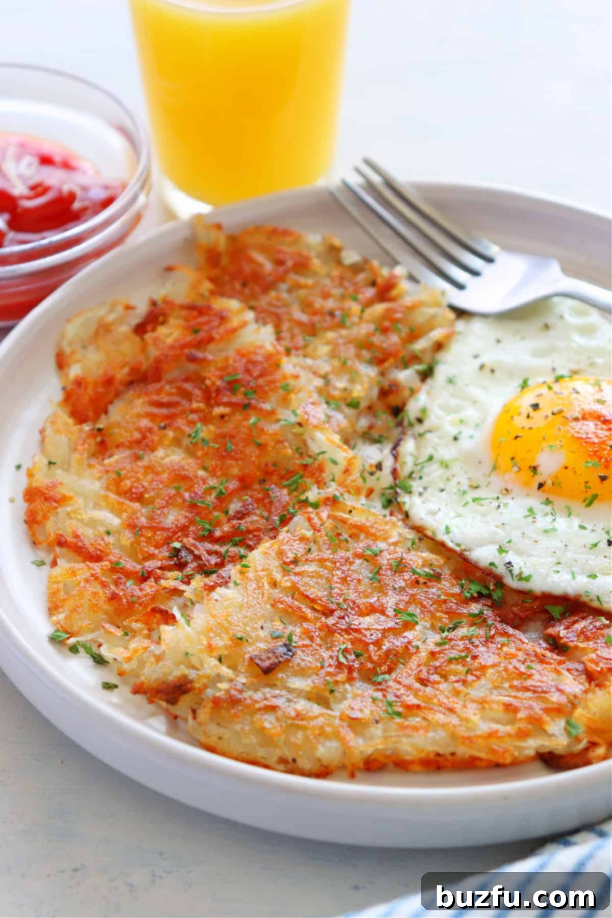 Best Homemade Hash Browns Recipe Golden brown crispy hash browns on a plate with a fried egg, ready for a delicious breakfast.