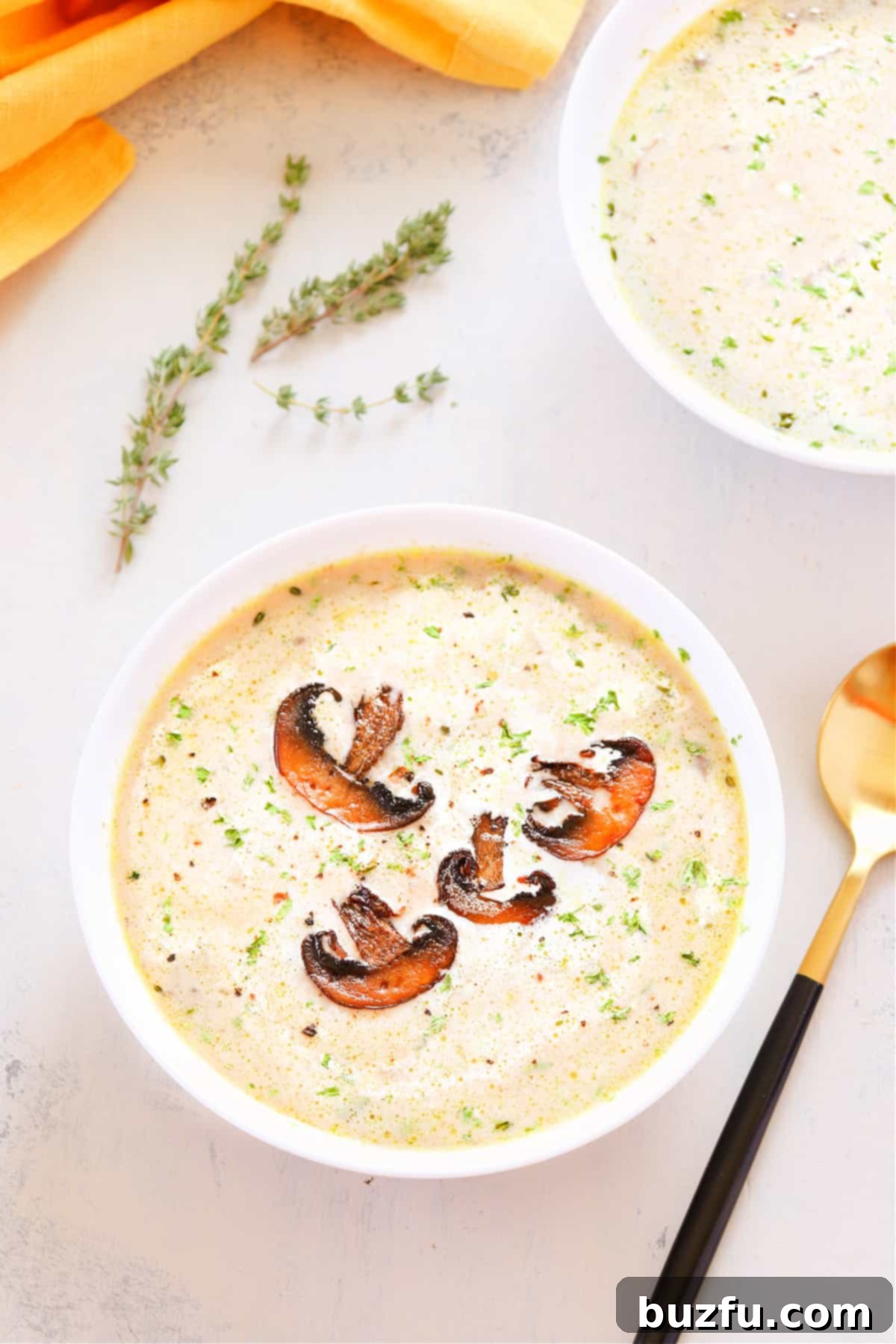 Creamy mushroom soup in a white bowl, garnished with fresh herbs and a swirl of cream.