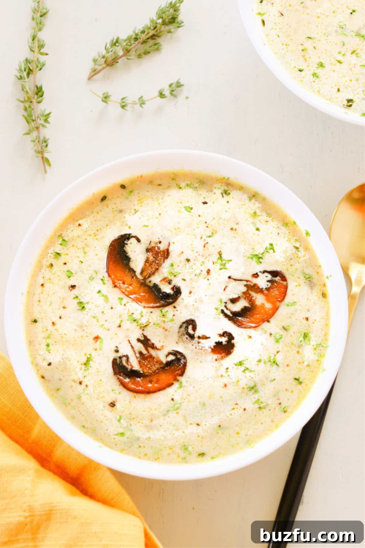 Close-up of a bowl of creamy mushroom soup garnished with parsley, showing its rich texture.