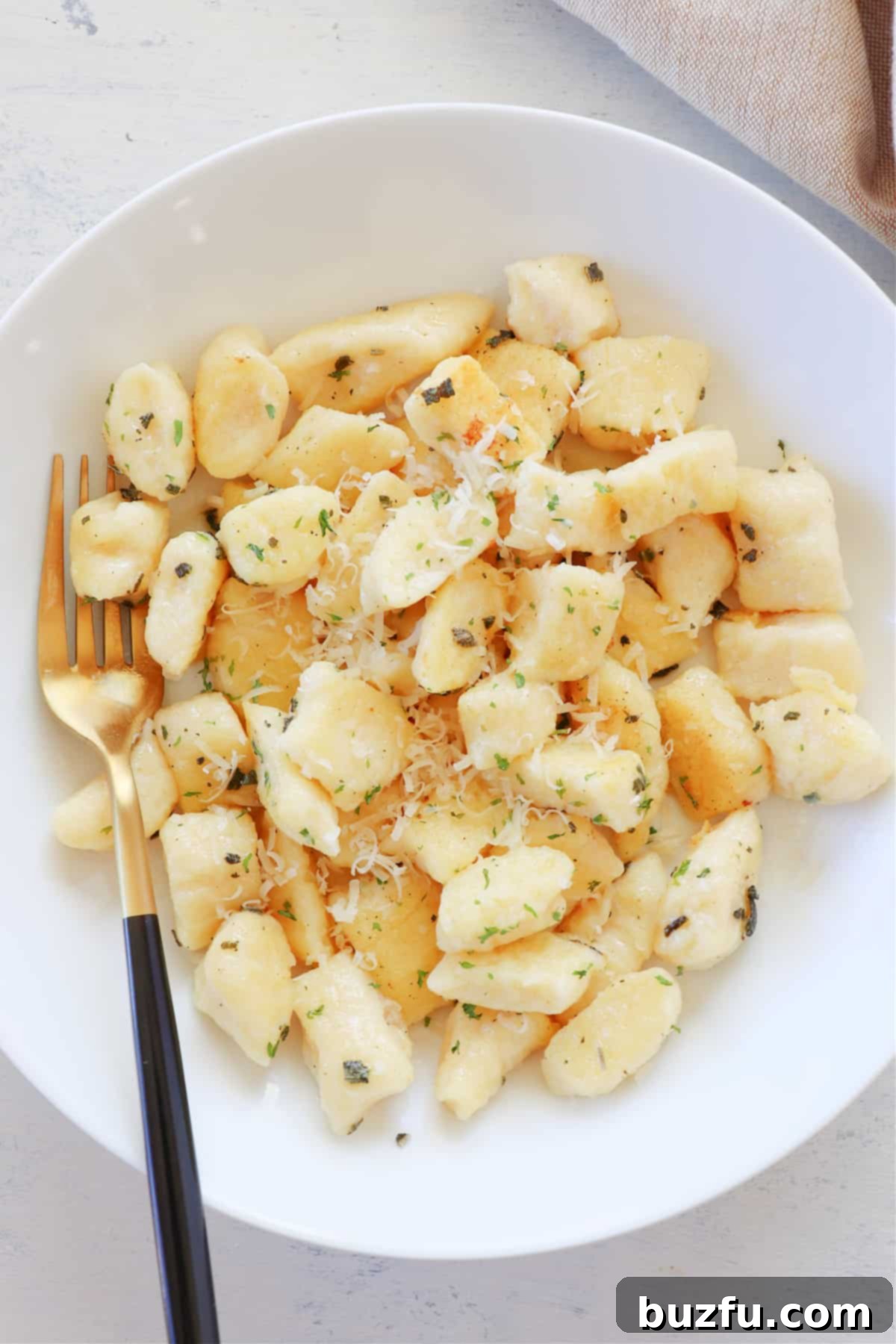 Pillow-Soft Ricotta Gnocchi Recipe Gnocchi in a white bowl, garnished with herbs.