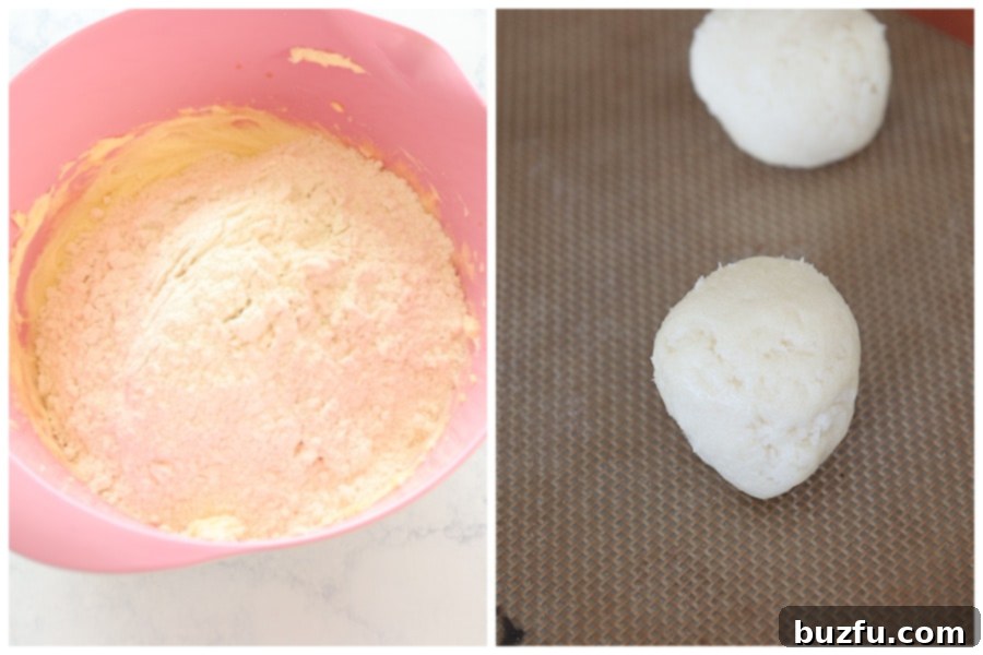 Scooped cream cheese cookie dough balls placed on a baking sheet lined with parchment paper, ready for baking.