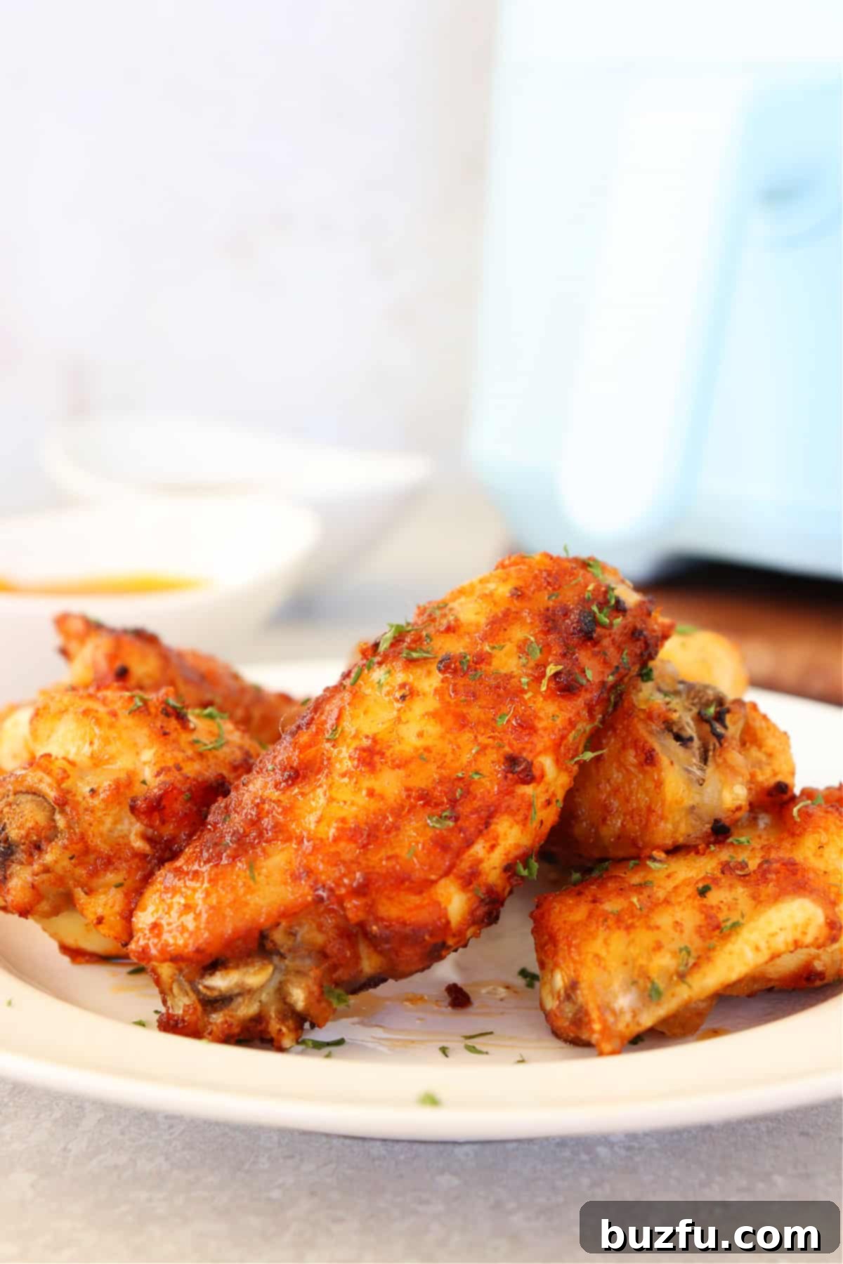 Crispy Air Fryer Chicken Wings Close-up of a perfectly crispy air-fried chicken wing on a white plate, highlighting its golden-brown skin and tender texture.