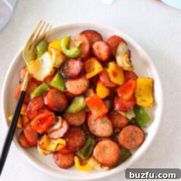 Effortless Air Fryer Sausage and Peppers 3 Air fried sausage and peppers on a plate with fork.