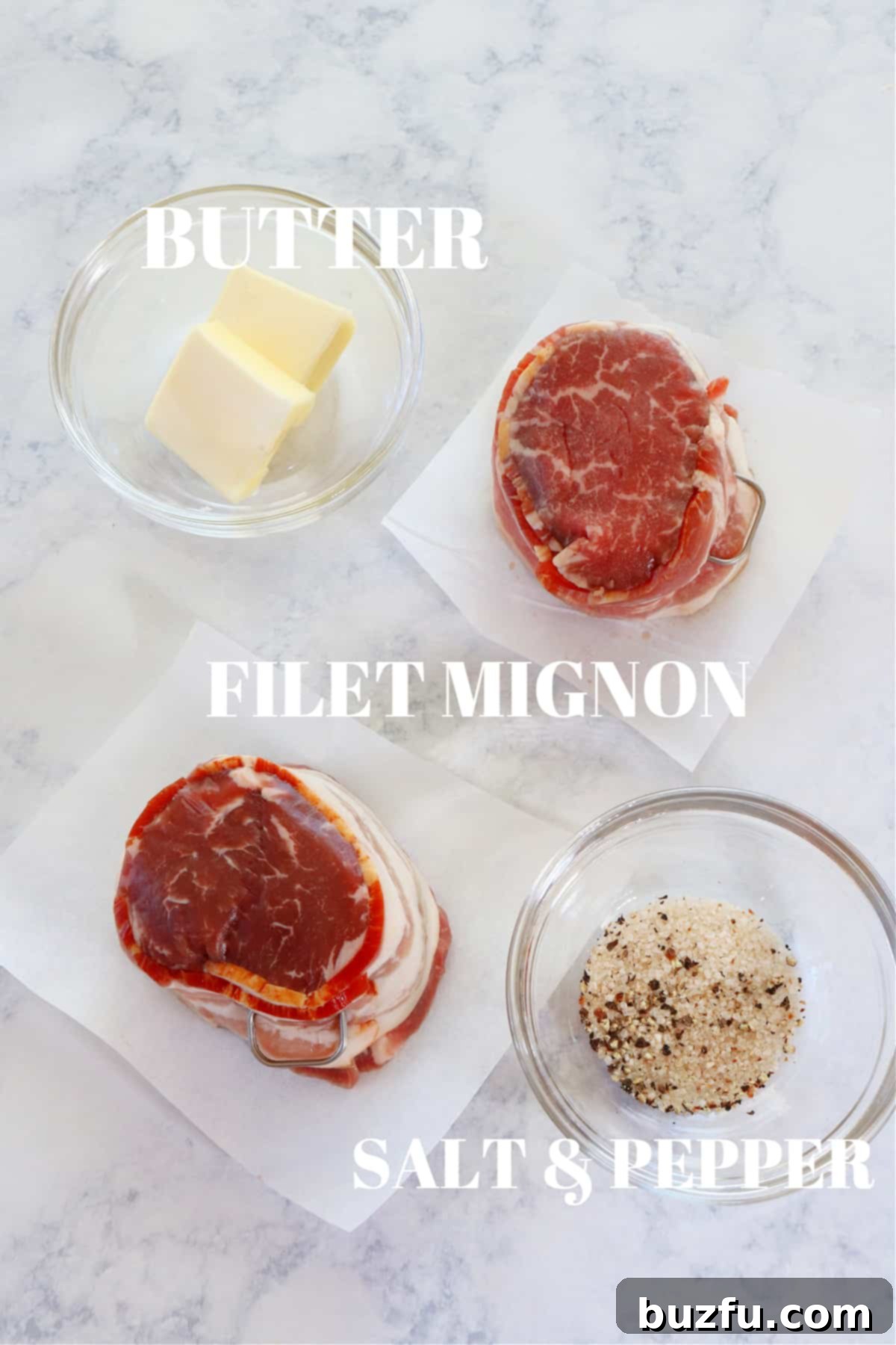Raw filet mignon, butter, and seasonings on a marble board, ready for preparation.