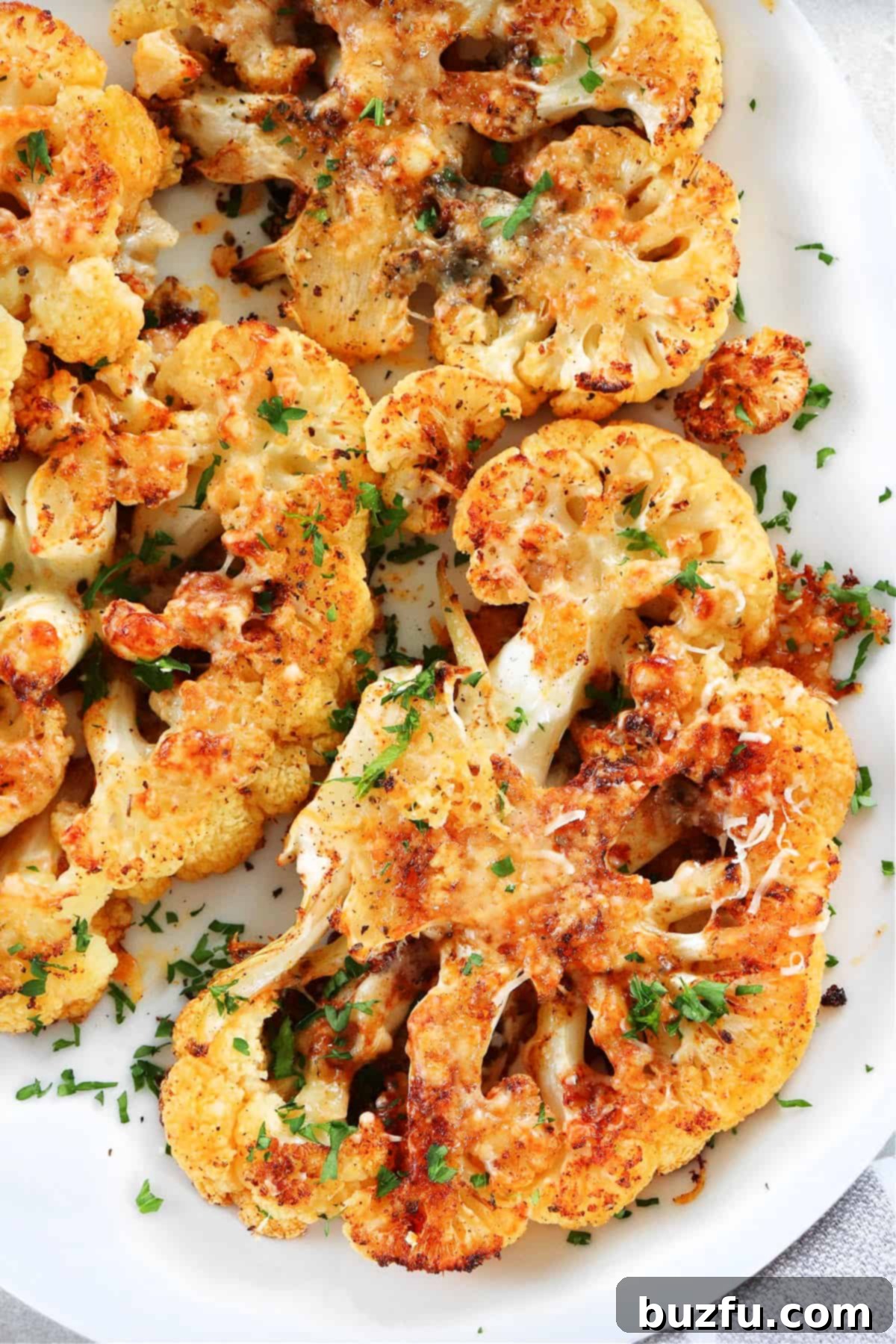 Easy and Delicious Cauliflower Steaks Beautifully roasted cauliflower steaks served on a large white platter, garnished and ready for a meal.