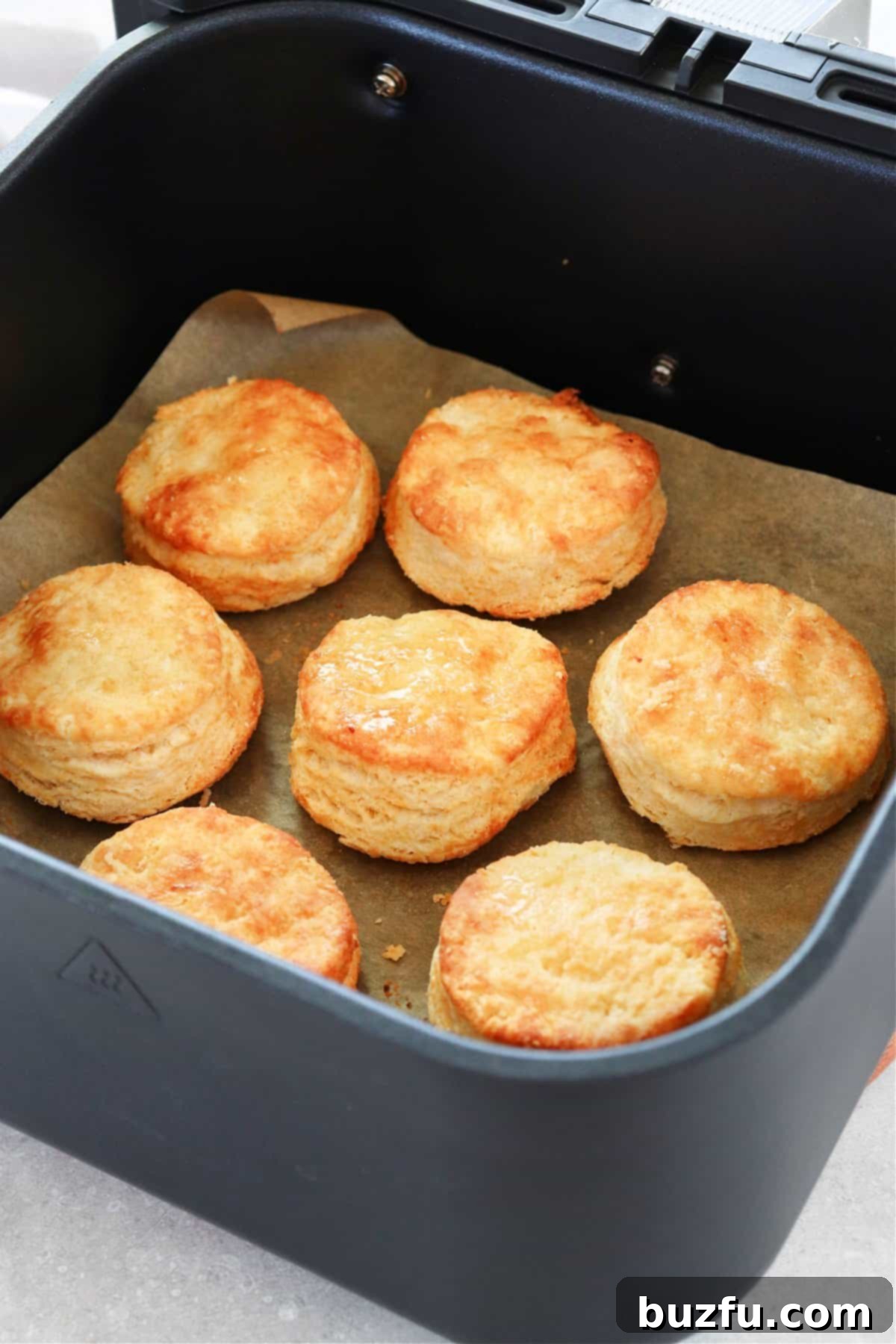 Air Fryer Biscuits from scratch. Baked biscuits perfectly golden and flaky, resting in the air fryer basket.