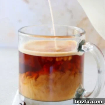 Coffee in a mug with creamer pouring in.