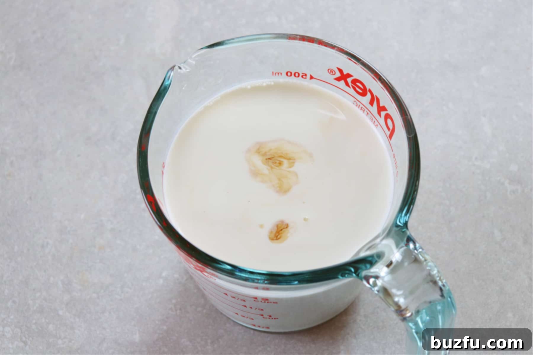 A glass measuring cup filled with freshly mixed, light brown homemade coffee creamer, ready to be transferred for chilling.