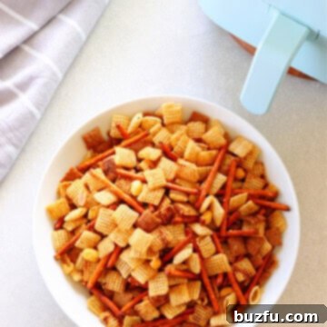 Party mix in white bowl next to air fryer.