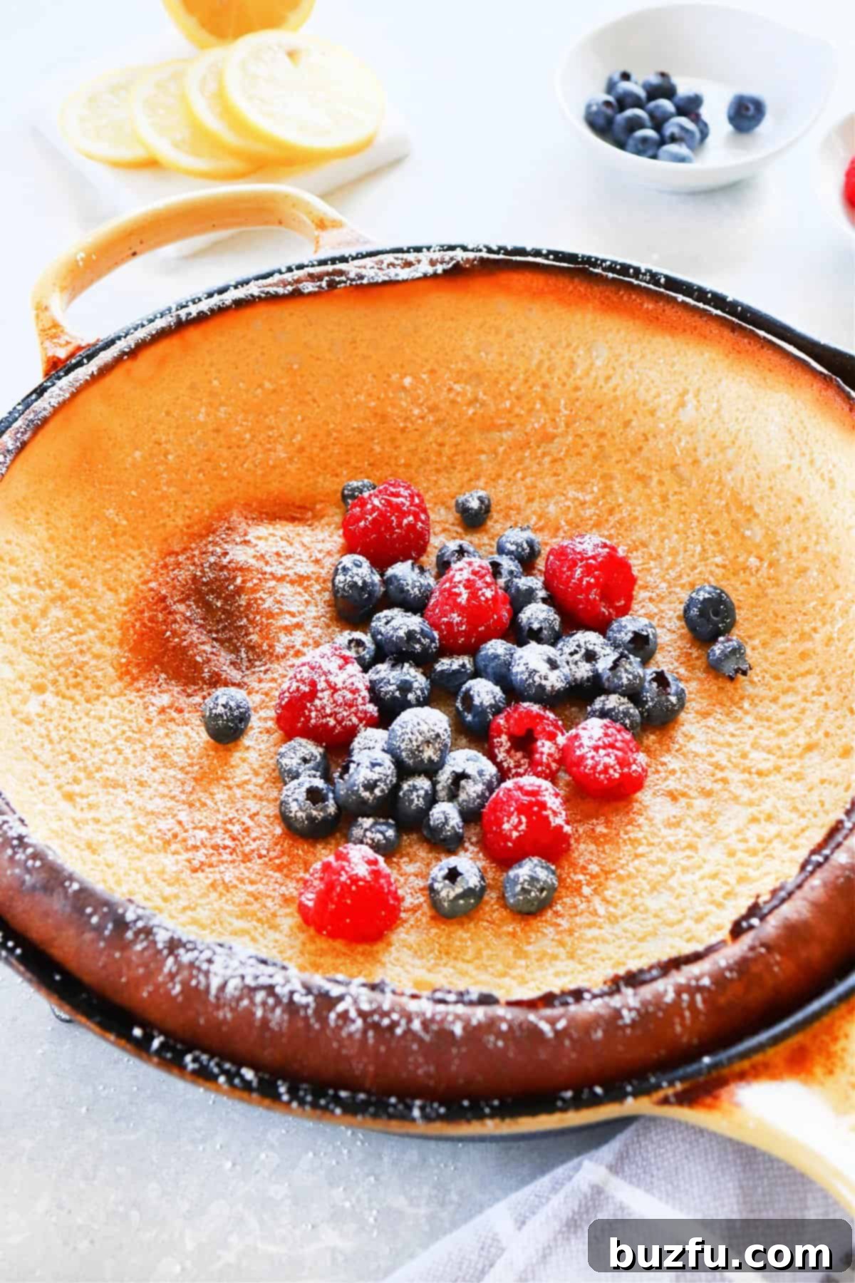 Golden-brown, puffed Dutch Baby Pancake in a cast iron pan, ready to be served for breakfast or brunch.