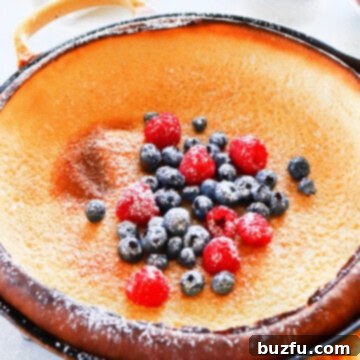 Dutch baby pancake in cast iron pan, ready for serving with toppings.