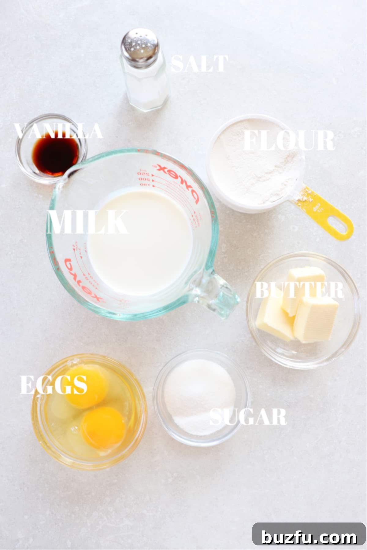 All the fresh ingredients needed for a homemade Dutch Baby Pancake displayed on a rustic gray board.