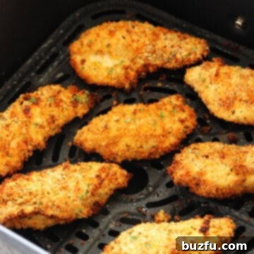 Crispy chicken tenders in an air fryer basket, ready to be removed.