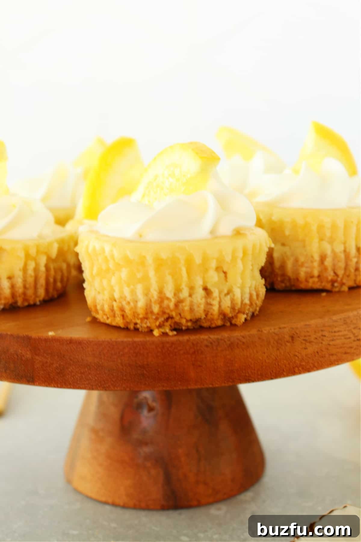 A collection of beautifully decorated mini lemon cheesecakes arranged on a elegant wooden cake stand, highlighting their individual charm and vibrant lemon accents.