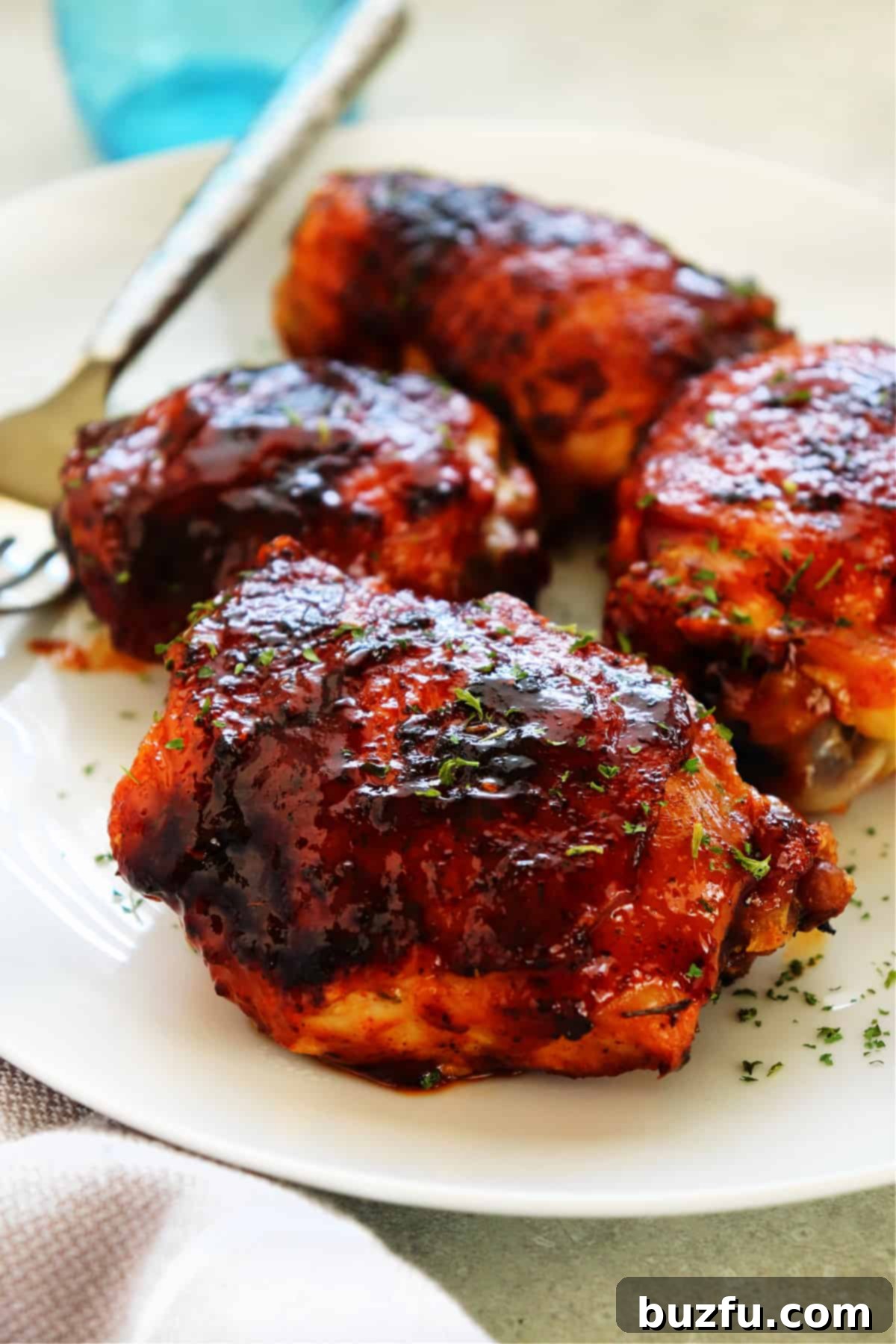 Air Fryer BBQ Chicken Thighs: A Family Favorite Recipe Perfectly glazed BBQ chicken thighs arranged on a pristine white serving platter, garnished with fresh herbs and ready for enjoyment.