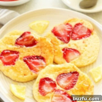 Pancakes with strawberry slices on a cream plate with fork.