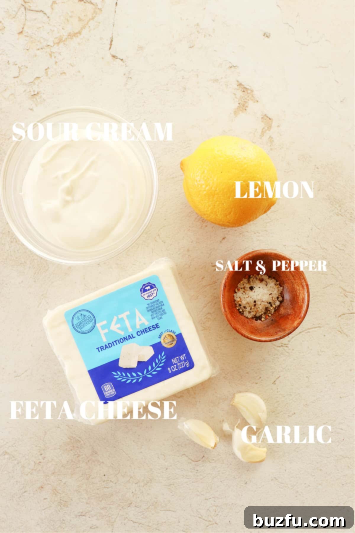 Feta, sour cream, lemon, garlic and salt and pepper on a cream board.