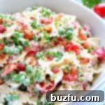 Pasta salad with bacon in a white bowl.