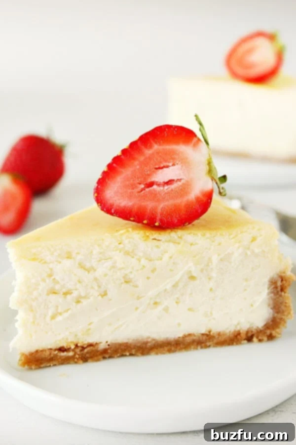 Cheesecake slice with strawberry on top, on white plate, highlighting a perfect, smooth texture.