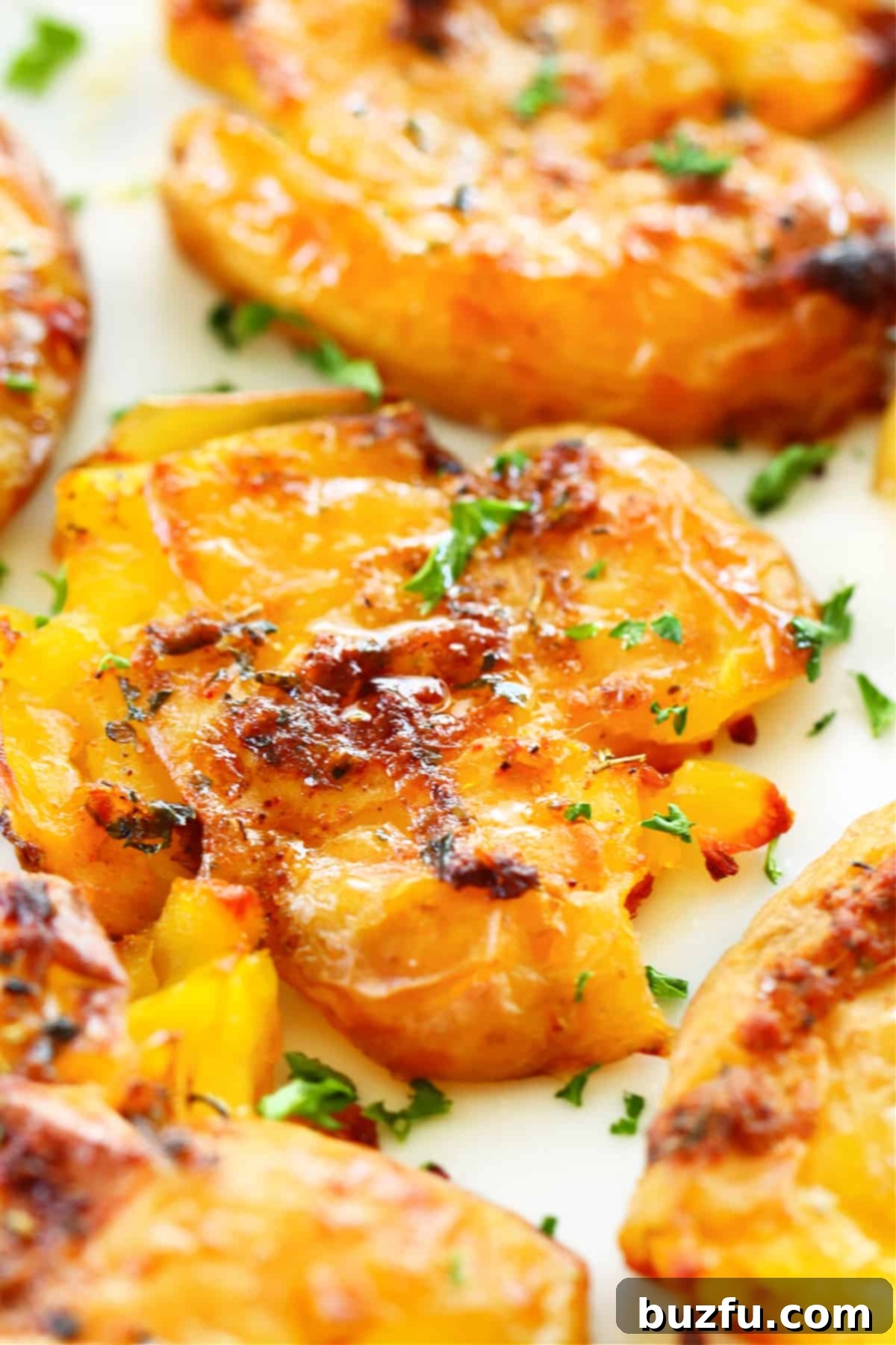 Effortless Crispy Smashed Potatoes 2 Close up photo of crispy smashed potato with garlic butter on parchment paper.