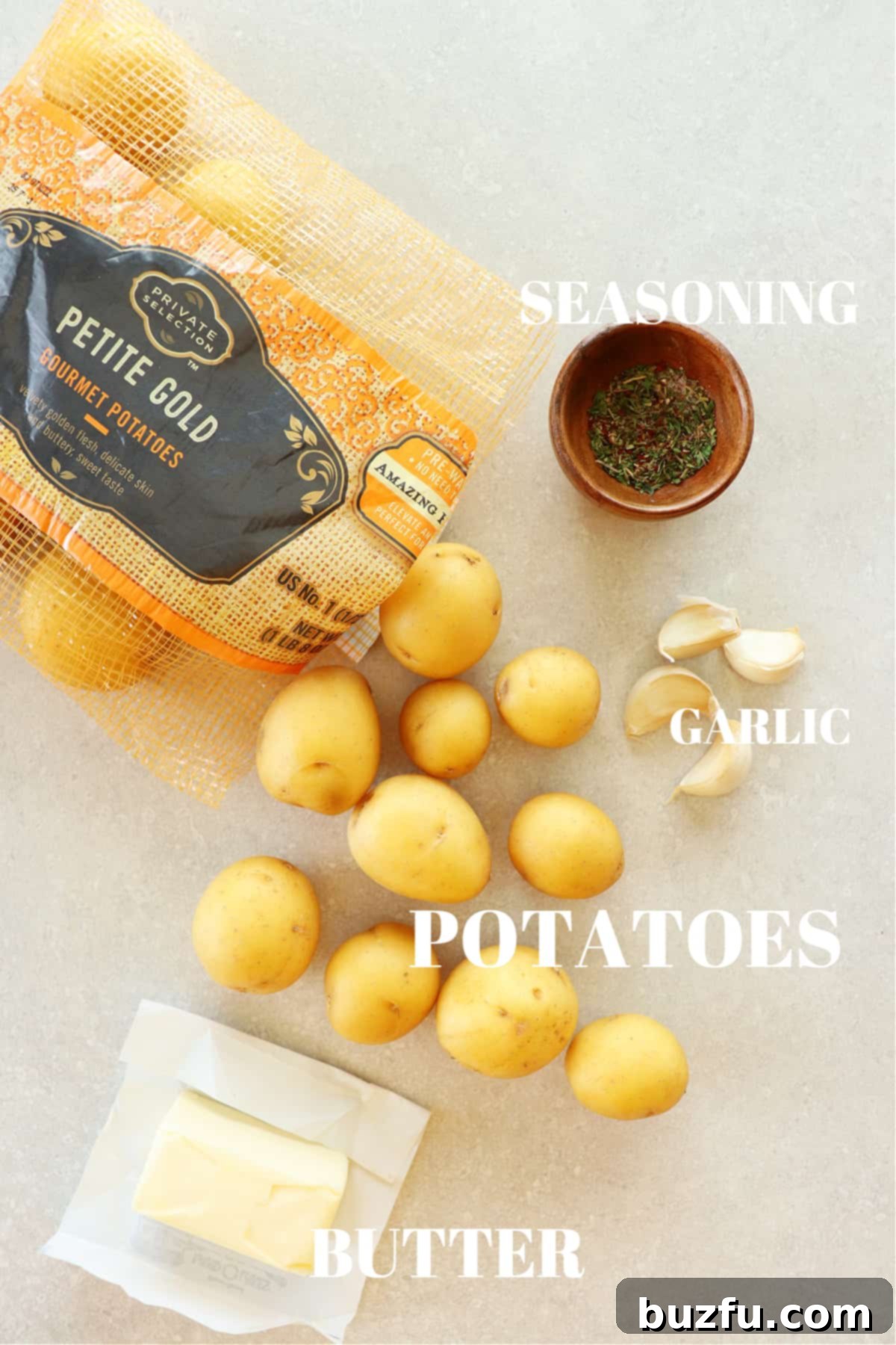 Effortless Crispy Smashed Potatoes 3 Baby potatoes, butter, garlic and seasoning in a wooden bowl on a gray board.