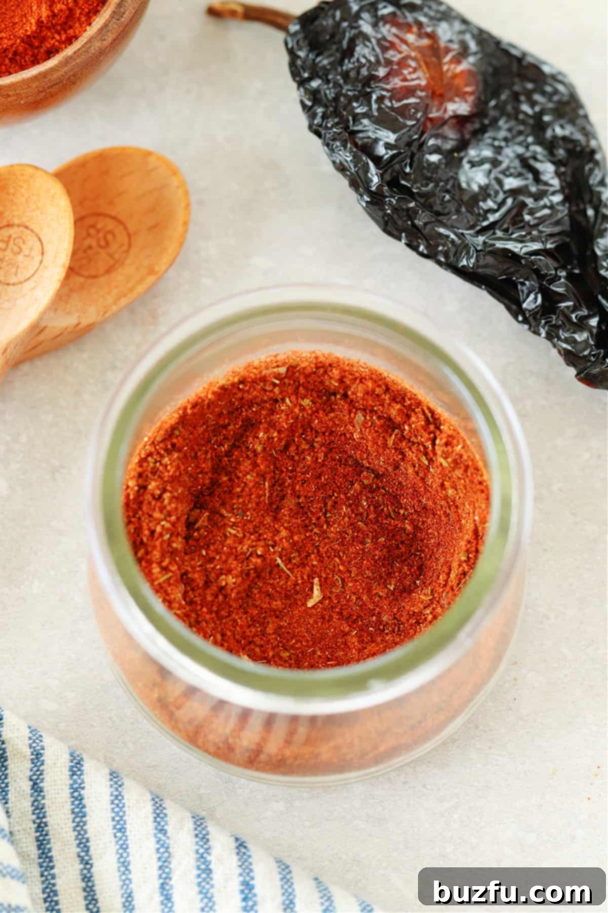 Craft Your Perfect Chili Blend 2 Close up photo of chili seasoning in a glass jar, on a gray board.