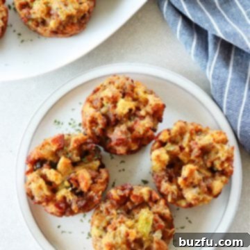 Savory Stuffing Cupcakes 7 Four golden-brown stuffing muffins on a white plate, showcasing their crispy tops, ready to be served.