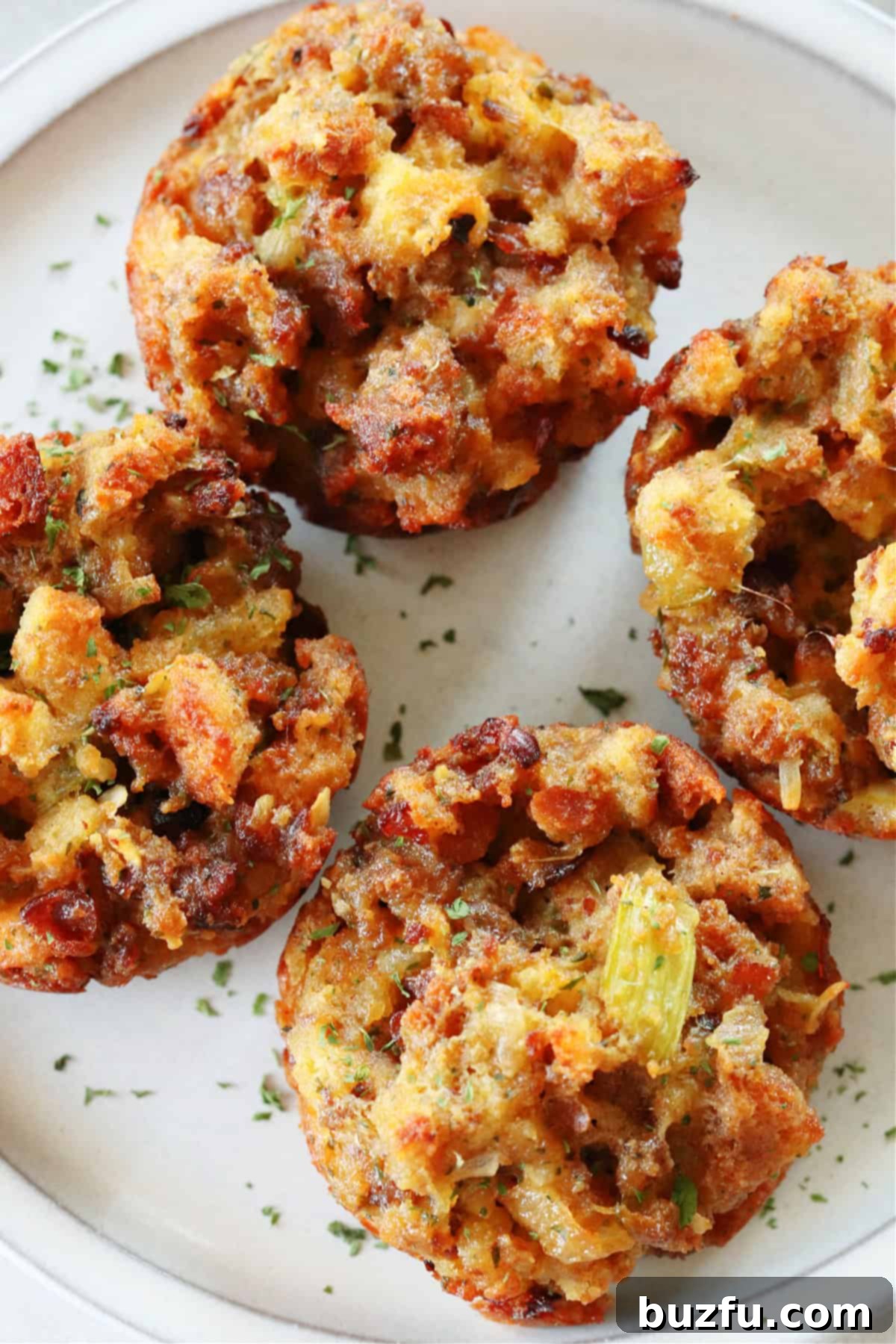 Savory Stuffing Cupcakes 5 A close-up shot of several stuffing muffins on a gray ceramic plate, showcasing their inviting texture and golden-brown crust, ready to be enjoyed.