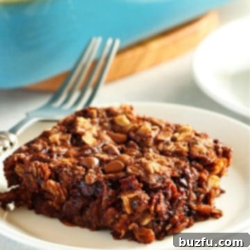 One serving of baked chocolate oatmeal on a small white plate with the baking dish in the background.