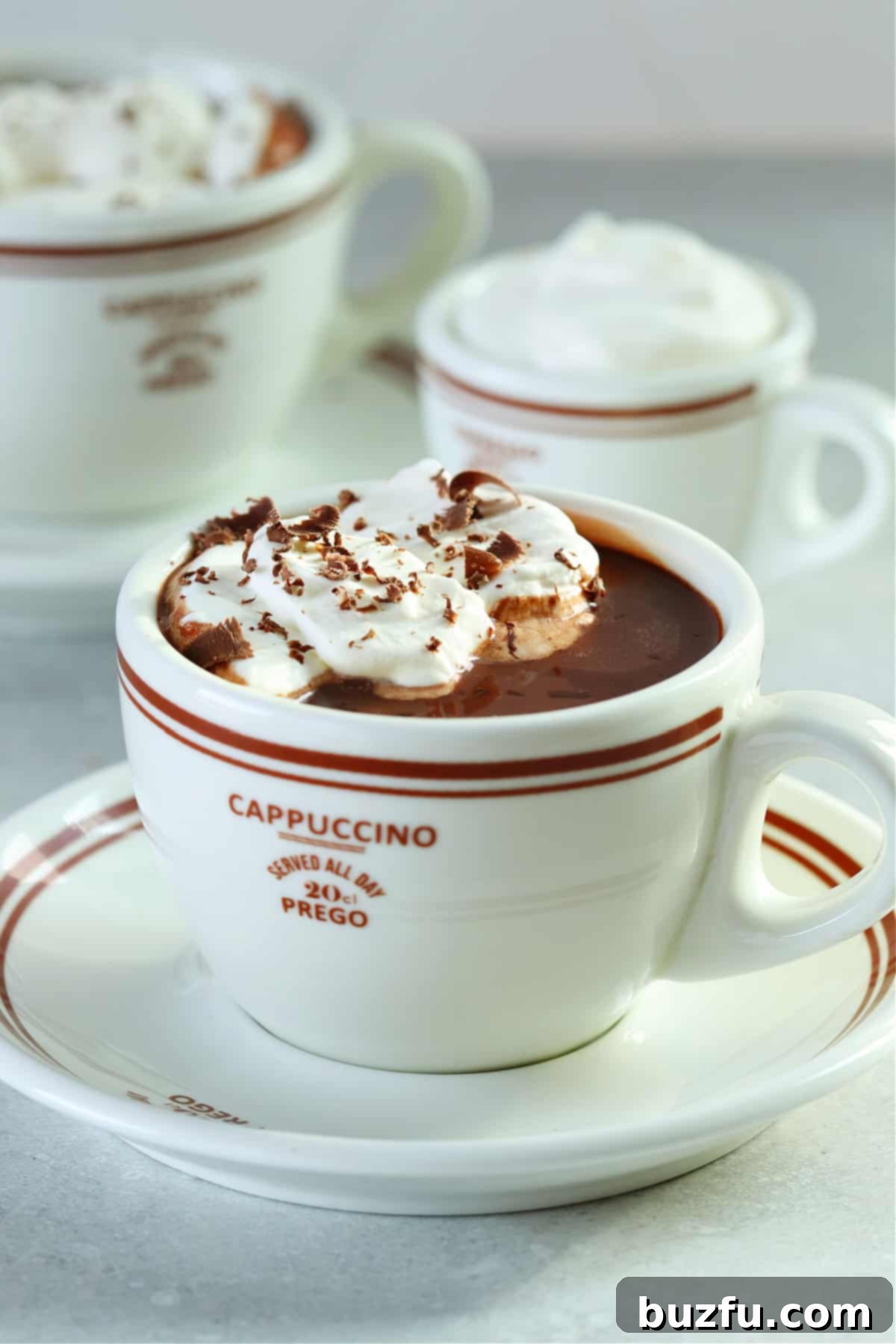 Hot chocolate in a mug on a saucer on a gray background.