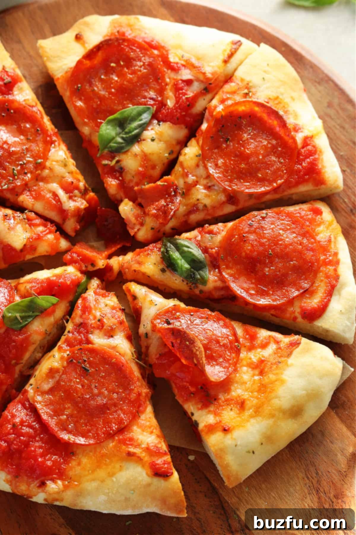 A delicious slice of pepperoni, mozzarella, and gouda cheese air fryer pizza on a round wooden cutting board.
