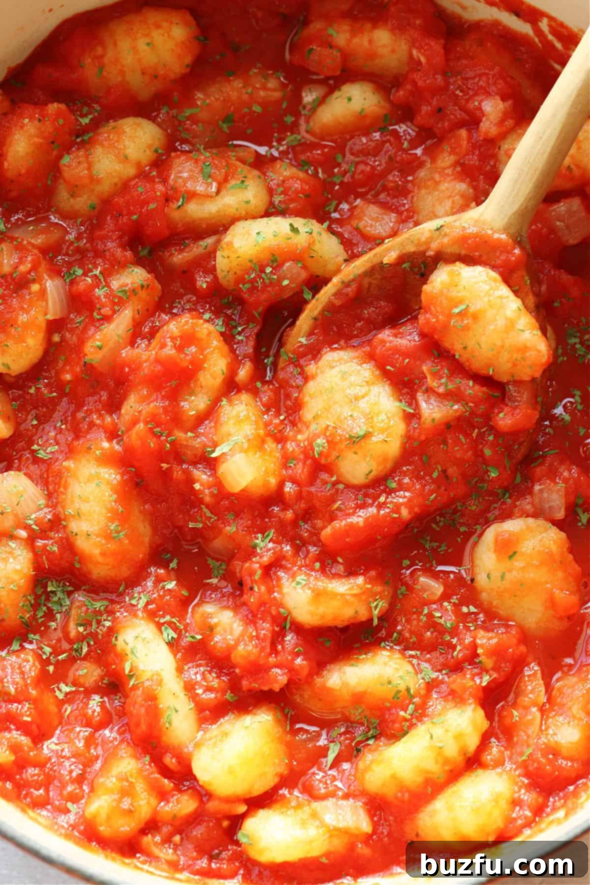 Gnocchi and tomato sauce in a pot with wooden spoon.