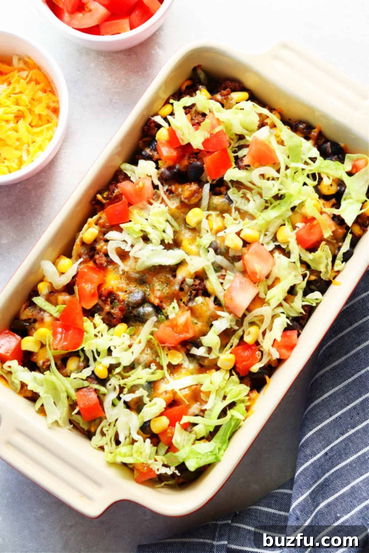 Hearty Taco Casserole in a rectangular baking dish, garnished with fresh tomatoes and vibrant green lettuce, ready to serve.