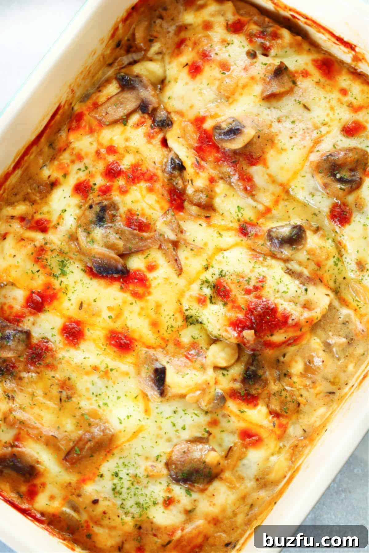 Chicken Gloria with melted cheese on top, in a rectangular baking dish.