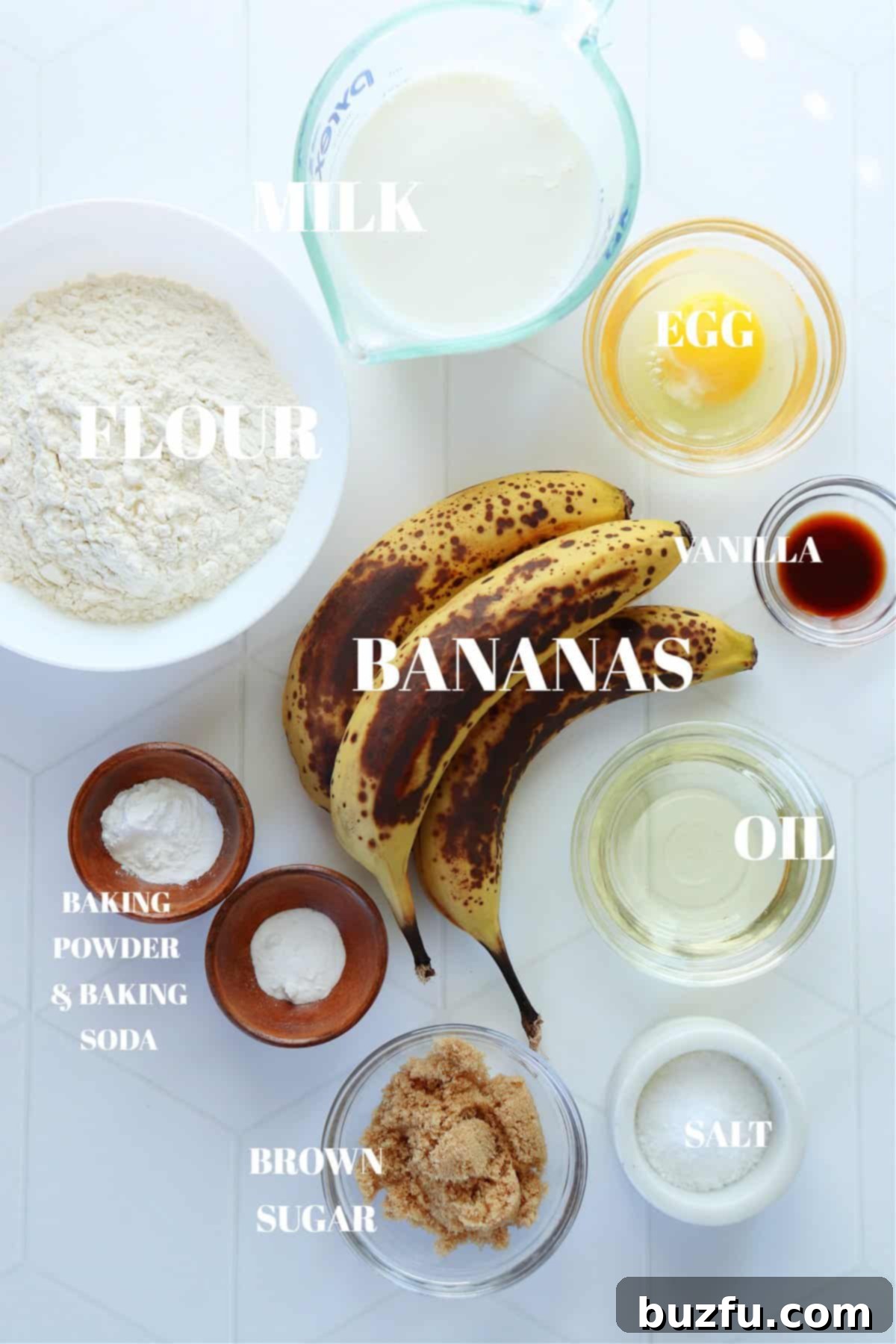 Golden Banana Pancakes 3 A flat lay photograph showcasing all the fresh ingredients required to make delicious banana pancakes, neatly arranged on a white tile board.